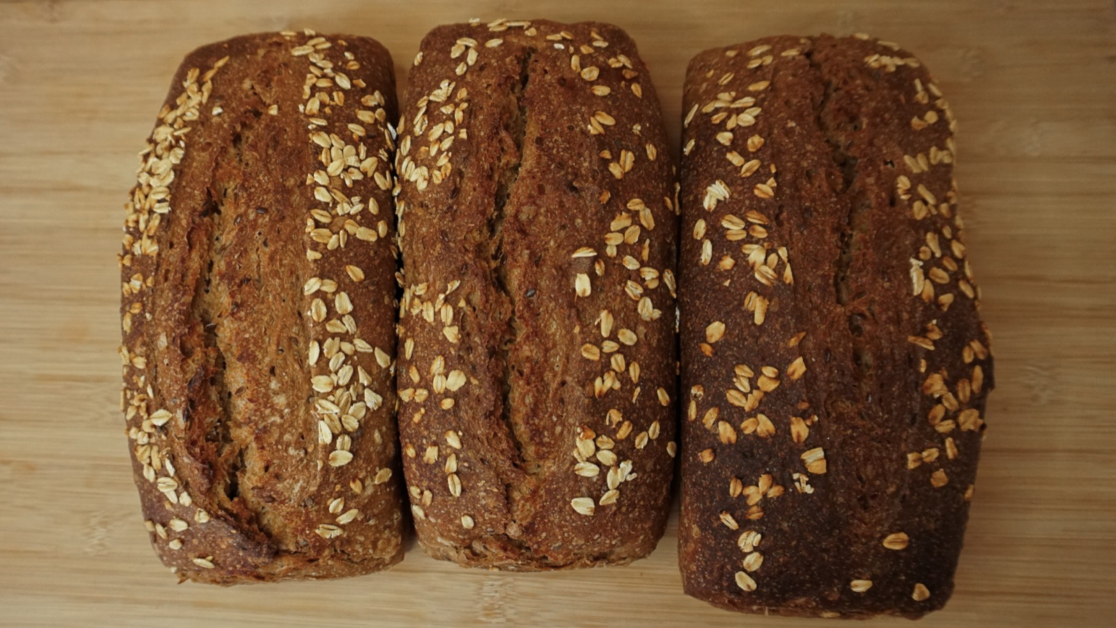 Tres panes de molde integrales con avena sobre tabla de madera